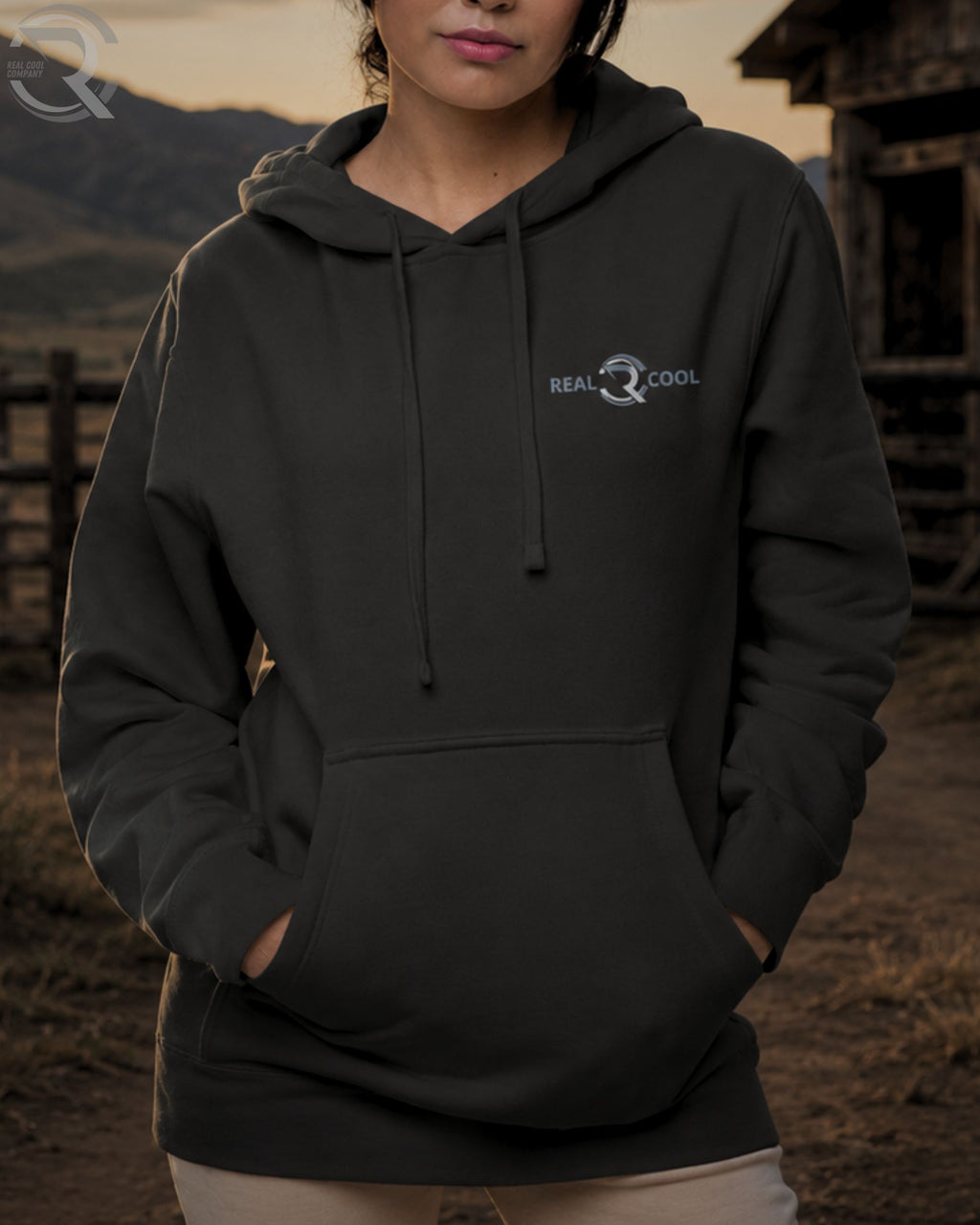 Person wearing a black hoodie with a logo in an outdoor setting